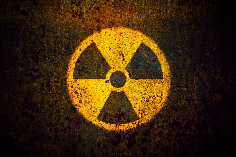 Preparing Seniors for a Nuclear DisasterRound yellow radioactive (ionizing radiation) danger symbol painted on a massive rusty metal wall with dark rustic grungy texture background with vignetting.