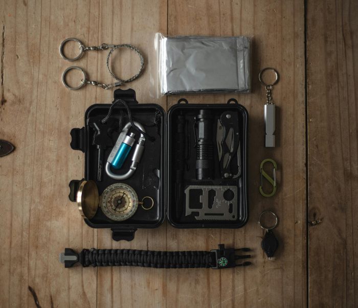 Best Survival Prepping Gear for SeniorsTop view of a compact survival kit with essential tools on a wooden surface.