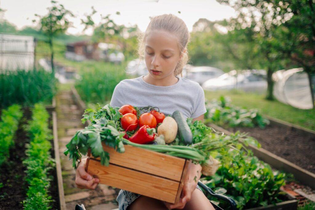 Why Being Self-Sufficient Is a Myth (and What to Do Instead)A young girl harvesting fruits and vegetables from a garden.